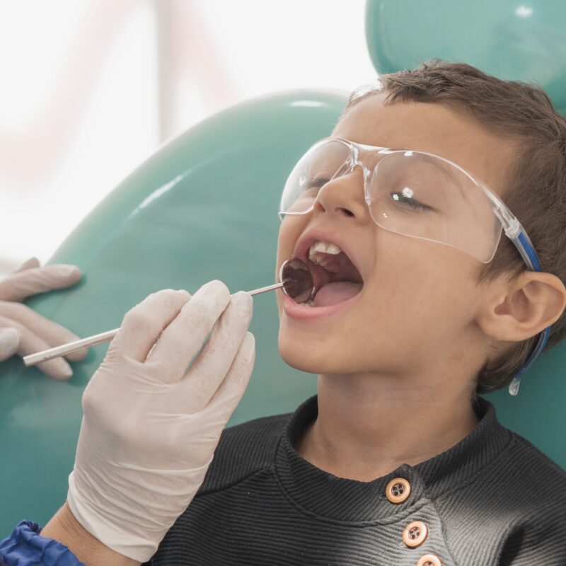 Toddler boy getting his teeth checked by a pediatric dentist in a the dental clinic