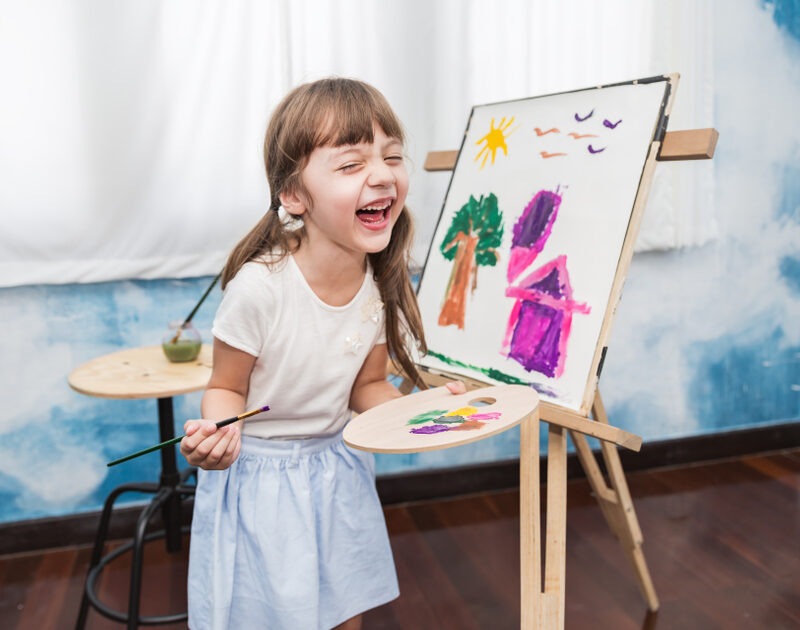 Young child painting and smiling during creative indoor activity representing fun kid-friendly activities in Missouri City